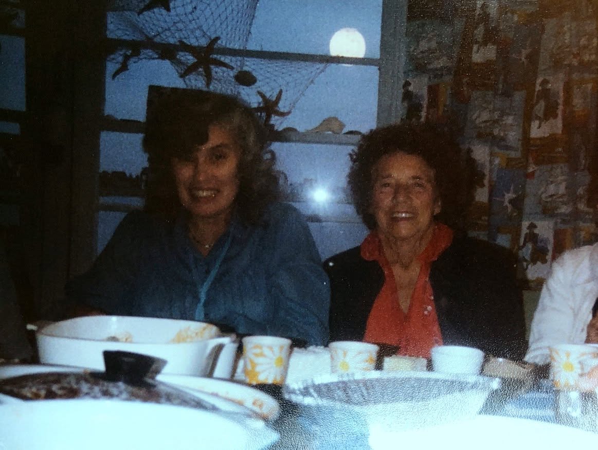 Two people smiling by a window